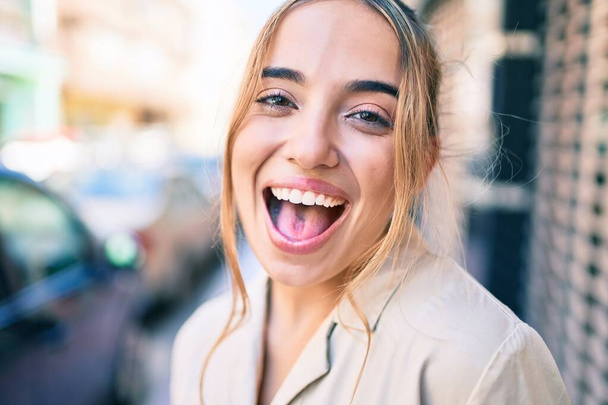 Young beautiful blonde caucasian woman smiling happy outdoors on a sunny day - Photo, Image