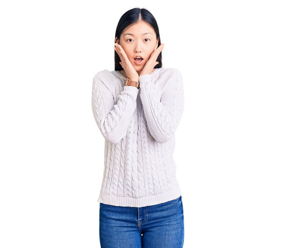 Молодая красивая китаянка в обычном свитере испугана и шокирована, удивлена и поражена выражением лица  - Фото, изображение