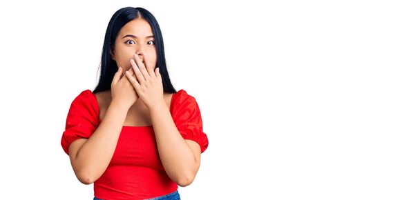 Junge schöne asiatische Mädchen in lässiger Kleidung schockiert Mund mit den Händen für Fehler bedecken. Geheimes Konzept.  - Foto, Bild