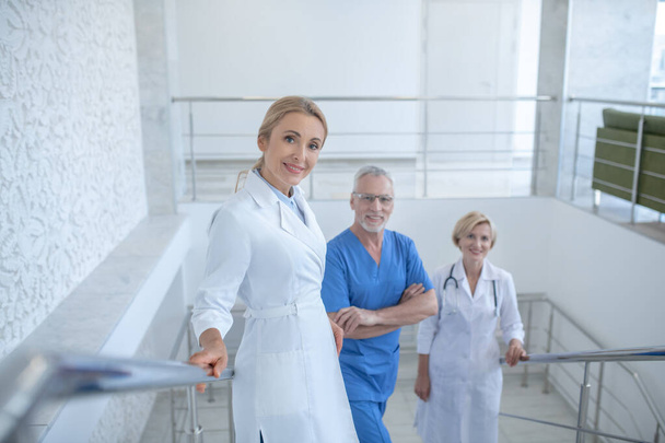 Group of smiling doctors standing on hospital stairs - Photo, image