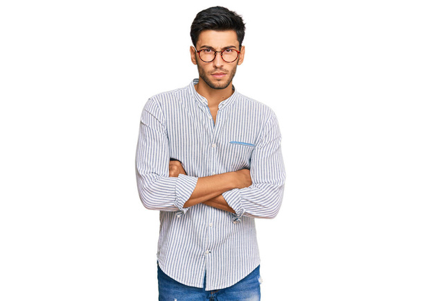 Jonge knappe man draagt casual kleren en glazen sceptisch en nerveus, afkeurende uitdrukking op gezicht met gekruiste armen. negatieve persoon.  - Foto, afbeelding