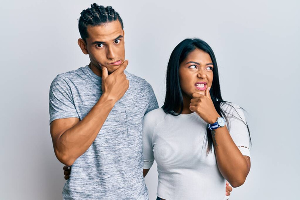 Young latin couple wearing casual clothes thinking worried about a question, concerned and nervous with hand on chin  - Foto, Bild