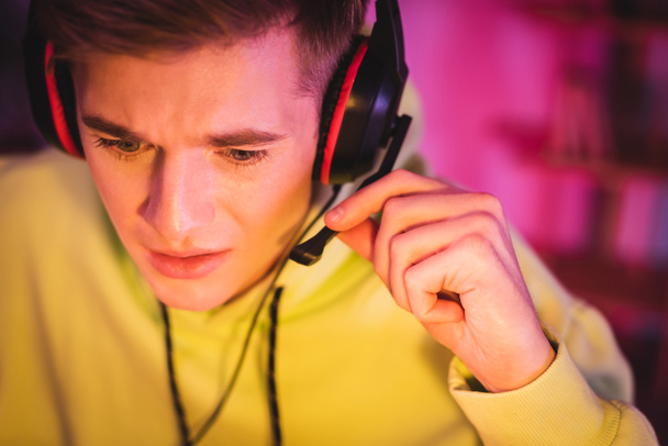 Young gamer holding microphone of headset and looking away  - Photo, Image