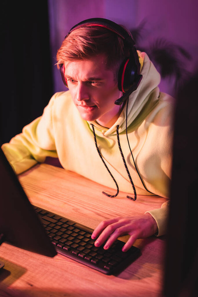 ビデオゲーム中にコンピュータキーボードを使用してヘッドセットの若い男  - 写真・画像