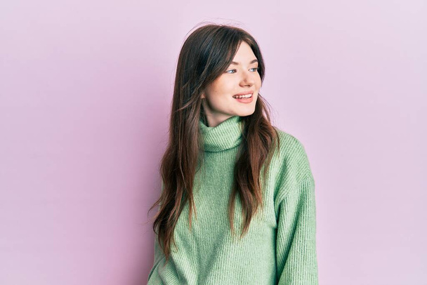 Jeune belle fille caucasienne portant un pull en laine regardant vers le côté, pose de profil relax avec visage naturel et sourire confiant.  - Photo, image