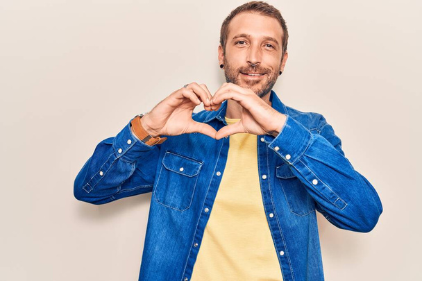 Young handsome man wearing casual clothes smiling in love showing heart symbol and shape with hands. romantic concept.  - Photo, Image