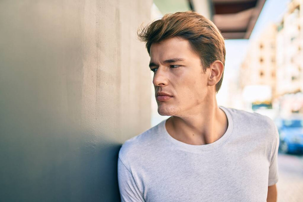 Young caucasian man with serious expression leaning on the wall at the city. - Foto, Imagem