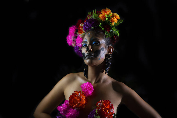 Retrato de sexi desnuda Catrina cubriendo su cuerpo con flores en la oscuridad de la noche - Foto, Imagen