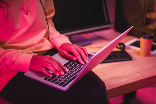 Обрізаний вид жінки, використовуючи ноутбук біля комп'ютера та кави, щоб піти на розмитому фоні
  - Фото, зображення