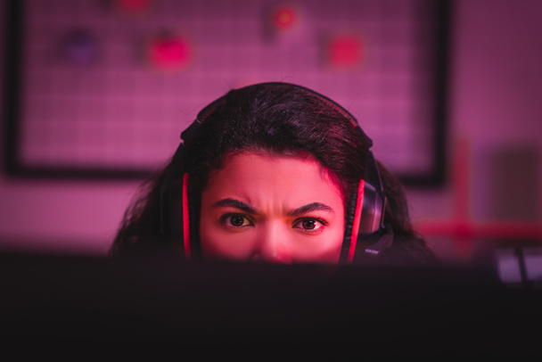 Зосереджений афроамериканець у навушниках дивиться на комп "ютер на розмитому передньому плані.  - Фото, зображення