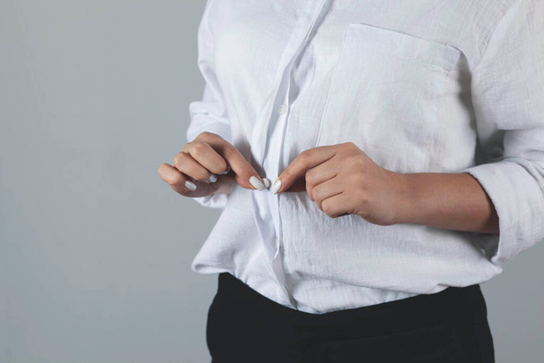 επαγγελματική γυναίκα χέρι κουμπί πουκάμισο σε γκρι φόντο - Φωτογραφία, εικόνα