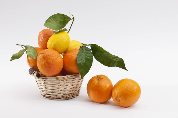 Citrus. Wicker basket of fresh citrus lemon and orange, isolated on a white background. Food concept. Citrus fruit and healthy food concept. - Fotó, kép