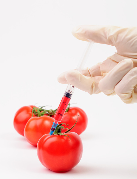 een rode injectie in een tomaat maken - Foto, afbeelding