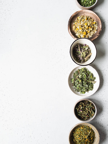 Různé suché zdravé byliny, rostliny květiny pro vaření bylinného čaje v miskách na šedém pozadí. Horní pohled. Kopírovat prostor - Fotografie, Obrázek