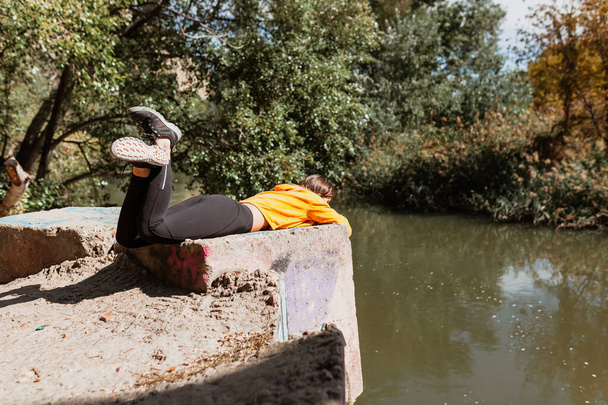 Woman resting near the bank of a river lying - Photo, Image