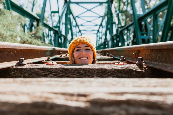 Vrouw heeft plezier in het verkennen van een oude, verlaten ijzeren spoorbrug - Foto, afbeelding