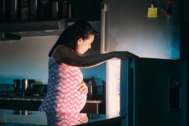 Kobieta w ciąży z Ameryki Łacińskiej jedząca w nocy - Zdjęcie, obraz
