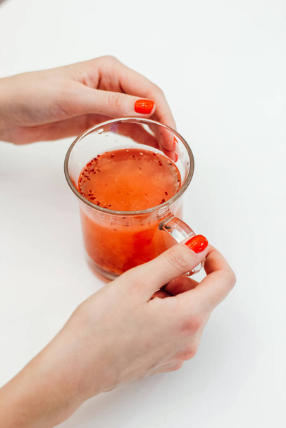 девушка с красным маникюром держа чашку с натуральным осенним ягодным чаем. - Фото, изображение