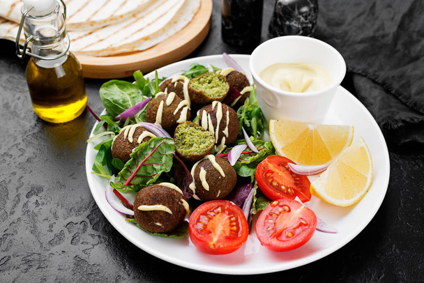 Yeşil salata, sos ve limonlu vejetaryen falafel.. - Fotoğraf, Görsel