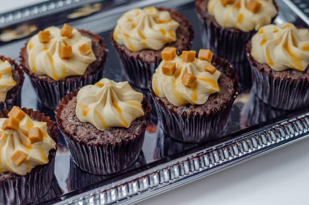 Солоні карамельні кекси на срібному підносі, спокусливі маленькі шоколадні кекси зі смаком коктейлів та карамельною мрякою, цукерки
 - Фото, зображення