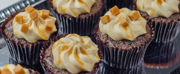 Sózott karamellás muffinok ezüst tálcán, csábító kis csokis muffinok, egy kis csokis cukormázzal és karamellás esővel, édességek. - Fotó, kép