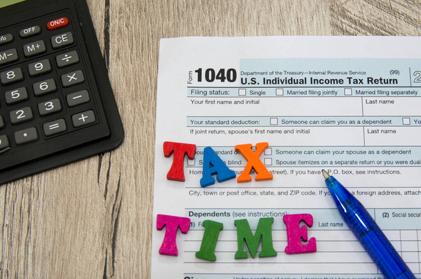 налоговые формы 1040 с калькулятором и ручкой на деревянном столе. Финансовый документ. - Фото, изображение