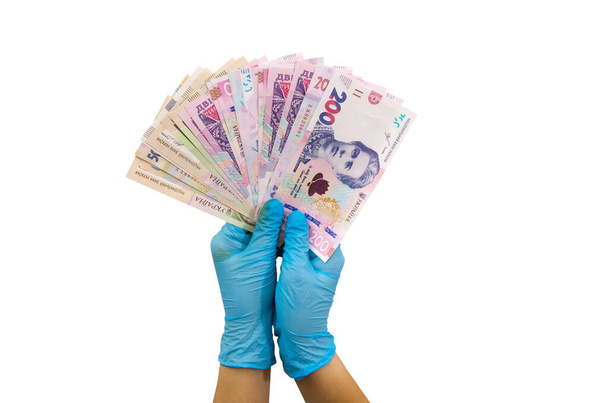 hands in blue medical gloves hold different hryvnia isolated on white background. - Photo, Image