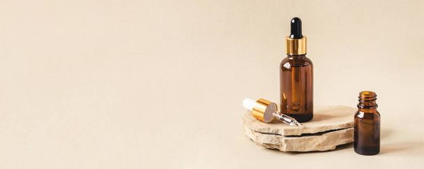 Dos botellas de cosméticos marrones sobre un fondo beige natural. - Foto, Imagen