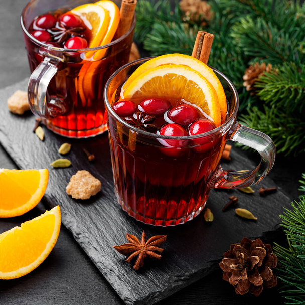 Karácsonyi forralt bor vagy gluhwein fűszerekkel és narancsszeletekkel. - Fotó, kép
