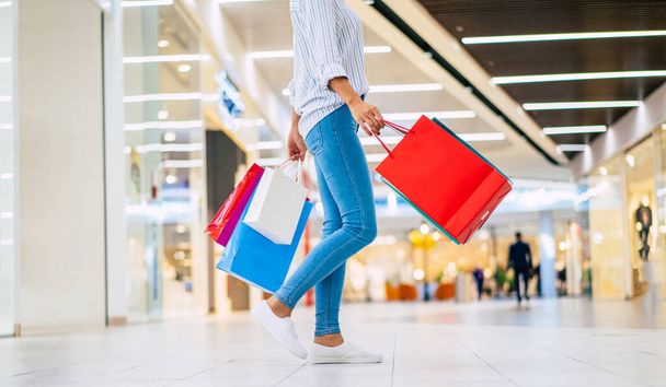 Cropped photo of cute glamour woman with bright colorful shopping bags while she walking on the mall - Fotografie, Obrázek