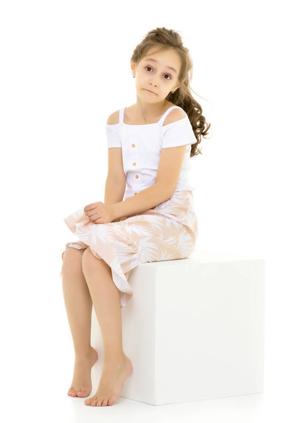 Portrait of Thoughtful Beautiful Girl Sitting on White Cube - 写真・画像