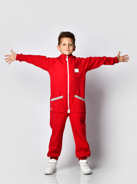 Boy in red warm jumpsuit showing victory gesture - Fotó, kép