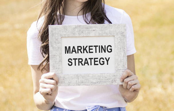 Cropped image of woman writing marketing strategy inscription isolated on white - Foto, Imagem