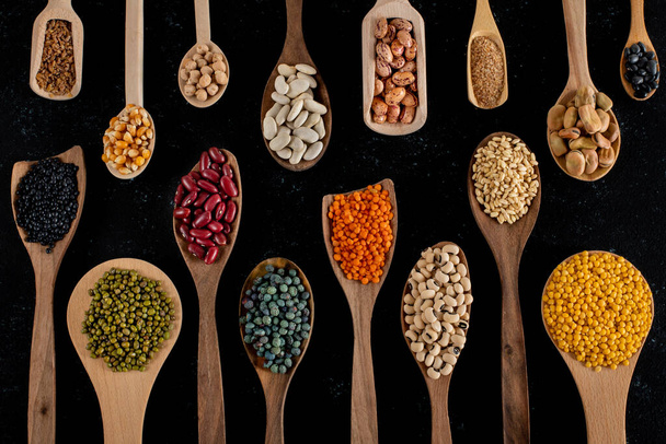 Large variety of dry beans with top view. Dried legumes in the wooden spoons.  - Photo, Image