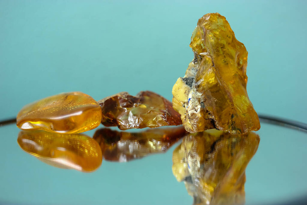 Кусок натурального янтаря на зеркальной поверхности, отражение желтого полудрагоценного камня - Фото, изображение