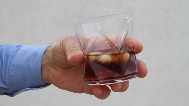 Férfi kéz örvénylik egy pohár whisky és jégkocka - Felvétel, videó