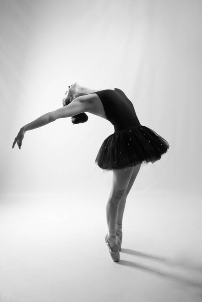 Schlanke junge Tänzerin, die auf Zehenspitzen tanzt und ein Kleid trägt, Studio, Lifestyle - Foto, Bild