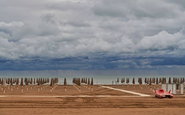 Sea view from an empty beach at the end of September in Caorle with  spectacular dense cloudy sky. - Photo, Image