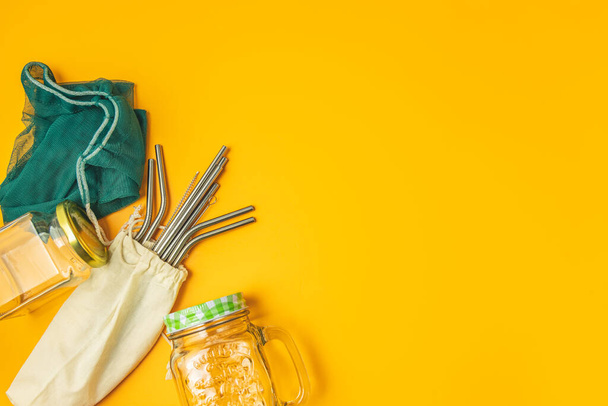 Zero waste concept. Cotton bag, bamboo cutlery, glass jar,  and straws on yellow background, flat lay,  copy space. Plastic free. - Valokuva, kuva
