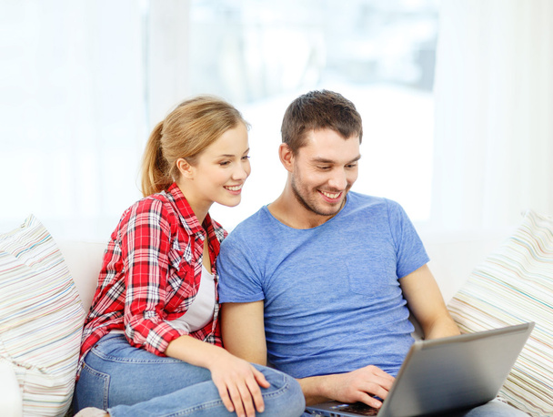 Smiling couple with laptop computer at home - Fotó, kép