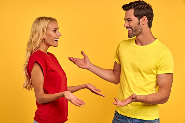 Seitenansicht des fröhlichen jungen Paares zwei Freunde Kerl Mädchen in lässiger Kleidung posiert isoliert auf gelbem Hintergrund. Menschen Lifestyle-Konzept. Attrappe Kopierraum. Sich anschauen, reden. - Foto, Bild