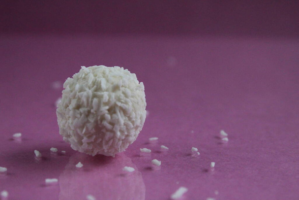 un bonbon blanc dans une noix de coco saupoudrer sur un fond d'espace de copie rose fuchsia - Photo, image