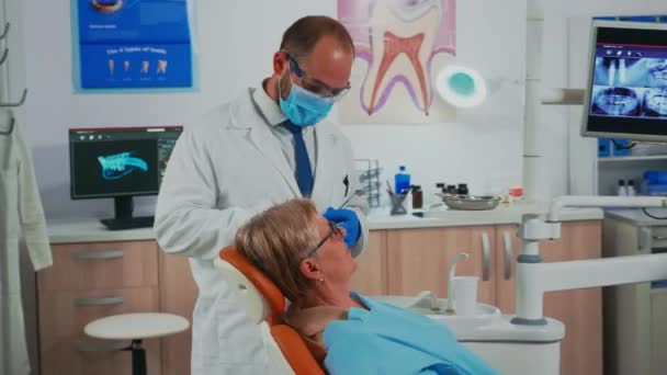 Ορθοδοντικός εξεταστής ασθενών που χρησιμοποιεί αποστειρωμένα οδοντιατρικά εργαλεία - Πλάνα, βίντεο