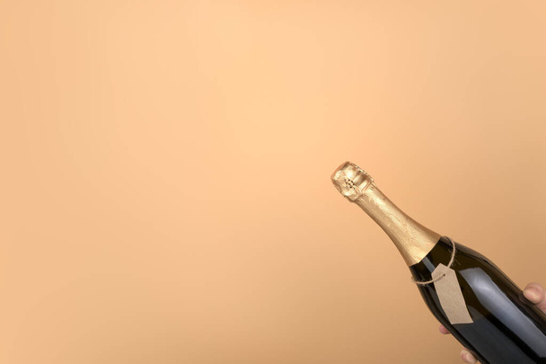 Шампанське в пляшці з етикеткою ручної роботи на персиковому фоні
. - Фото, зображення