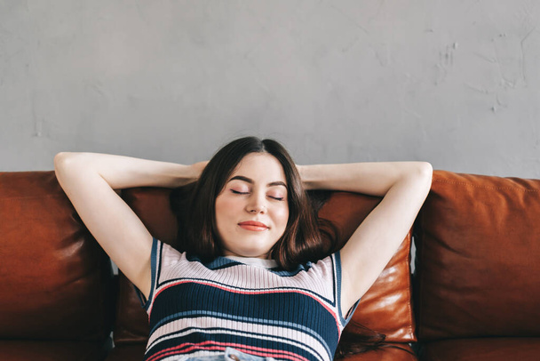 Young calm caucasian woman relaxing lying on comfortable sofa in modern living room, lazy happy woman resting on couch at home. High quality photo - Fotografie, Obrázek