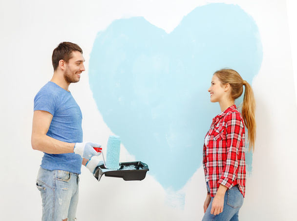 Smiling couple painting big heart on wall - Zdjęcie, obraz