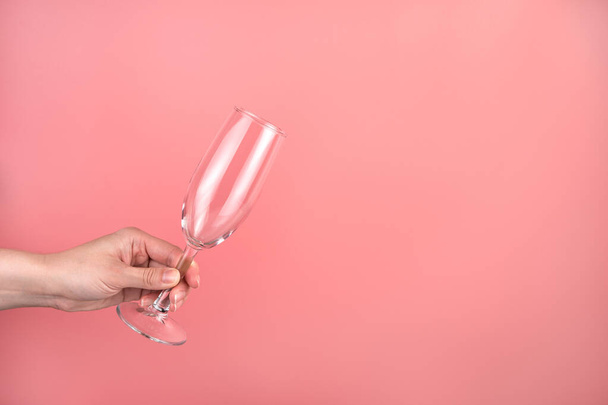 Champagne glas in de hand van een vrouw op een roze achtergrond. - Foto, afbeelding