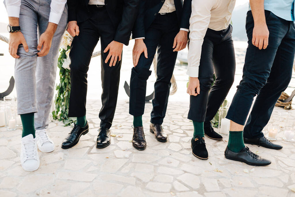 A vőlegény és a legjobb férfiak azt mutatják, hogy ugyanazt a zöld zoknit viselik. - Fotó, kép