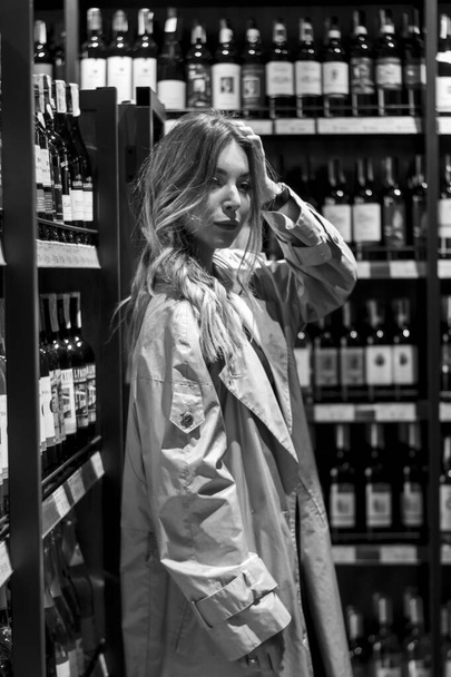 seksikäs houkutteleva nainen viinikaupassa keskuudessa hyllyt viiniä. mustavalkoinen valokuva. pehmeä fokus - Valokuva, kuva