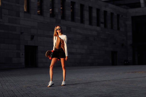 Young woman rides a longboard around the city. - Foto, imagen